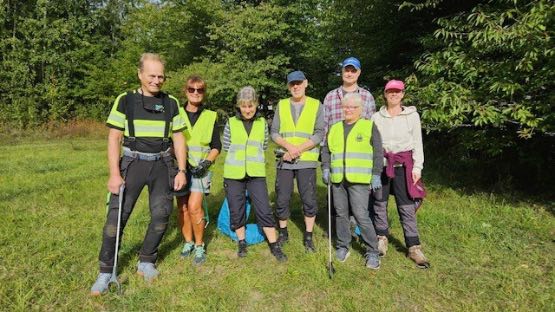 Åtta tappra skräpplockare poserar på midsommarängen